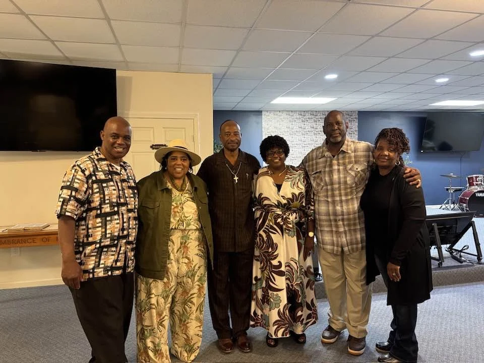 Six adults smiling together in the House of Miracles sanctuary